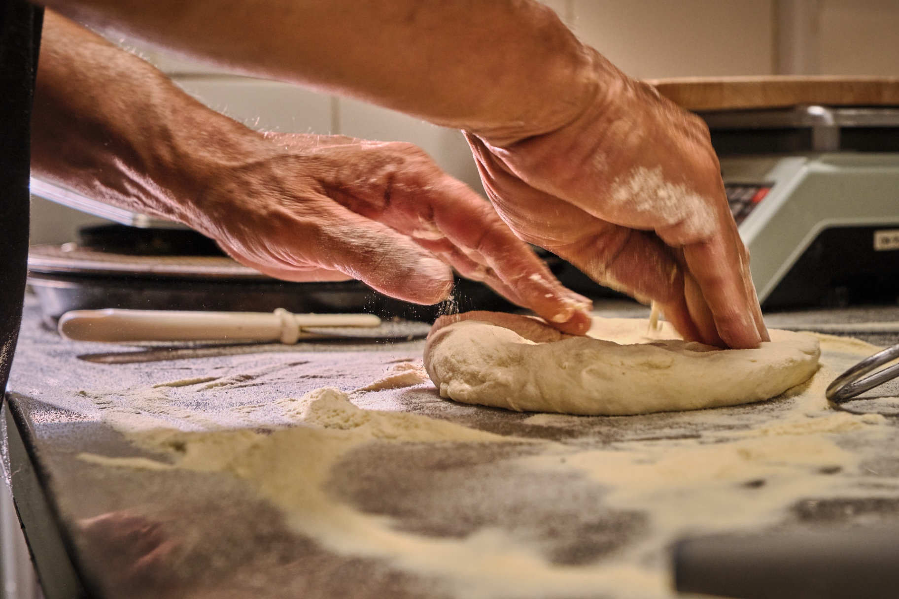 Manos formando el borde de una pizza sobre harina